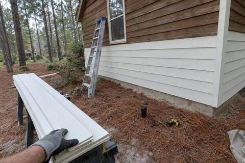 Fresh fiber-cement lap siding going up beside an old stained cedar section