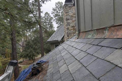 Gray slate roof along a hip line with copper flashing