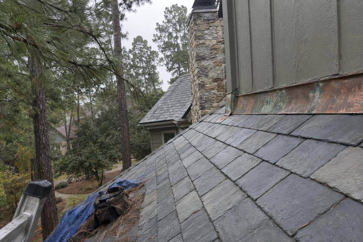 Gray slate roof along a hip line with copper flashing on a custom home